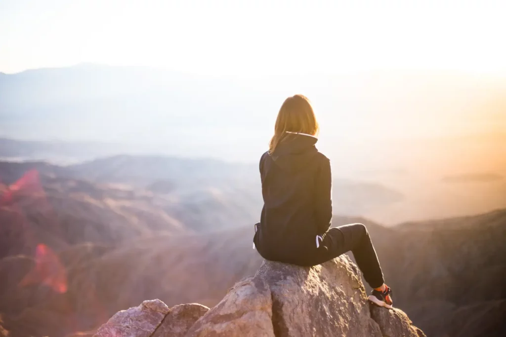 femme sur un sommet face à l'immensité des montagnes pour se ressourcer